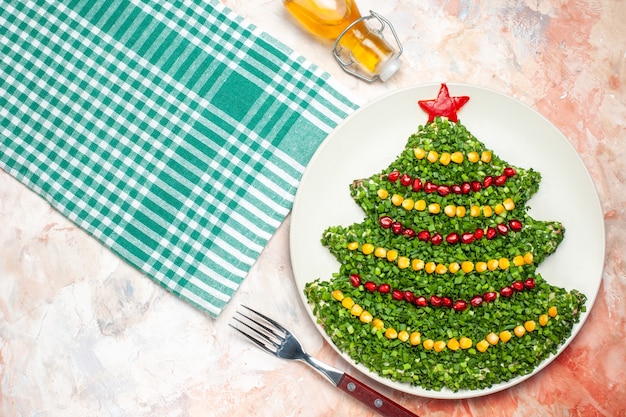 Bovenaanzicht smakelijke groene salade in de vorm van de nieuwe jaarboom op lichte achtergrond