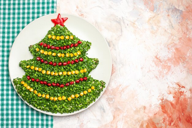 Bovenaanzicht smakelijke groene salade in kerstboomvorm op de lichte achtergrond