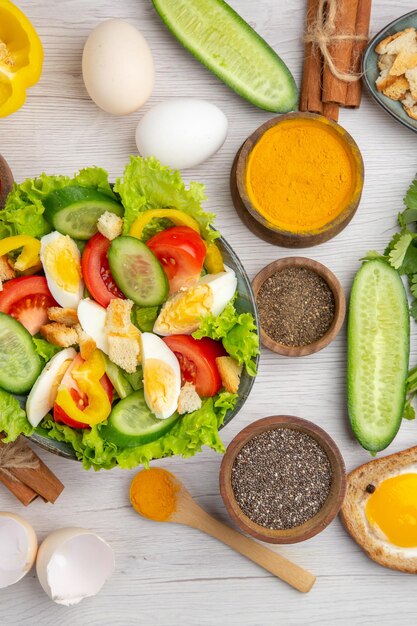 Bovenaanzicht smakelijke groentesalade met eieren, kruiderijen en tomaten op de witte achtergrond voedselkleur rijp ontbijt lunch maaltijdsalade