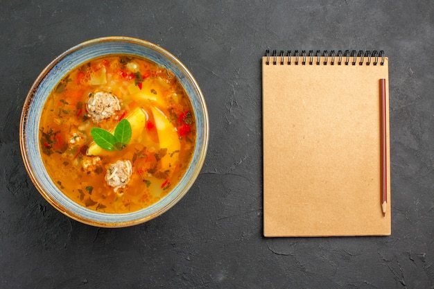 Bovenaanzicht smakelijke groentesoep met vlees en aardappelen op donkere tafel schotel vleesmeel eten