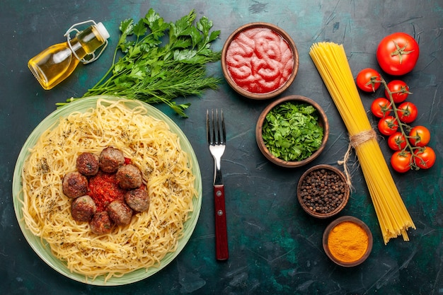 Bovenaanzicht smakelijke Italiaanse pasta met gehaktballen en verschillende kruiden op het donkerblauwe bureau