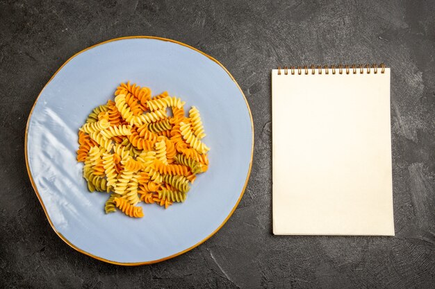 Bovenaanzicht smakelijke Italiaanse pasta ongebruikelijke gekookte spiraalvormige pasta op donker bureau