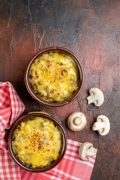 Gratis foto bovenaanzicht smakelijke julienne in kommen champignons op donkerrode tafel