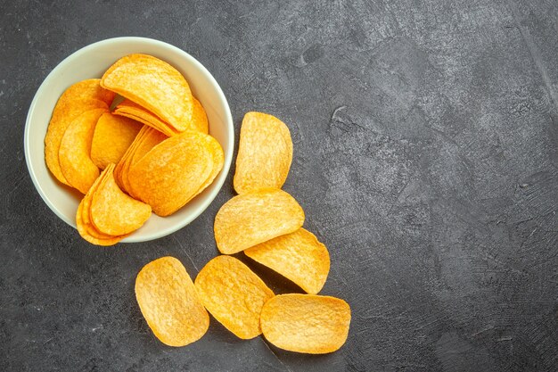 Bovenaanzicht smakelijke kaas cips binnen plaat op een donkere achtergrond