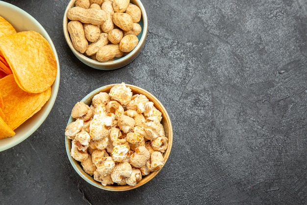 Bovenaanzicht smakelijke kaaschips met verschillende snacks op de donkere achtergrond