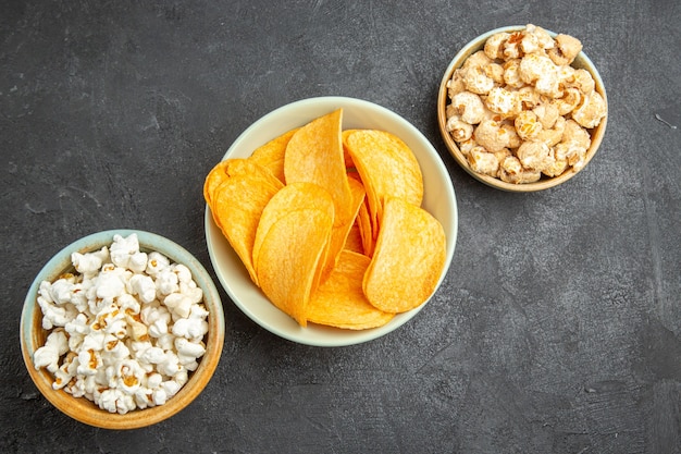 Bovenaanzicht smakelijke kaaschips met verschillende snacks op de donkere achtergrond