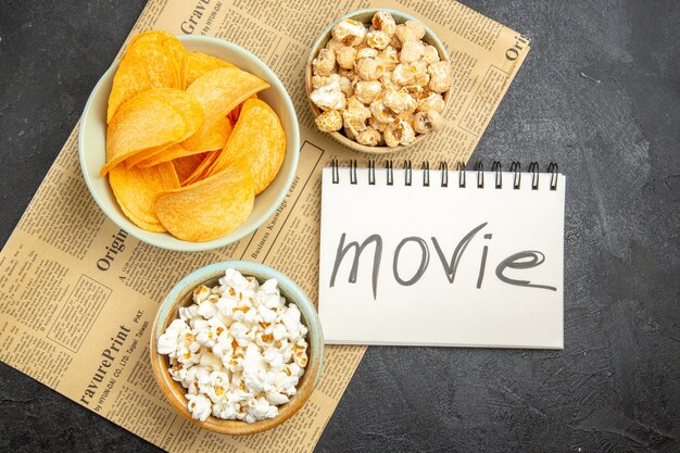 Bovenaanzicht smakelijke kaaschips met verschillende snacks voor filmtijd op de donkere achtergrond