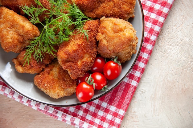 Gratis foto bovenaanzicht smakelijke kippenvleugels met greens en tomaten op lichte achtergrond sandwich vlees lunch diner frietjes hamburger maaltijd