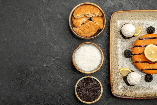 Bovenaanzicht smakelijke kleine taart met kokossnoepjes op donkere oppervlakte taart dessert cake biscuit thee snoep