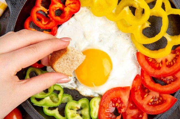 Bovenaanzicht smakelijke omelet met tomaten en gesneden paprika op de donkere tafel