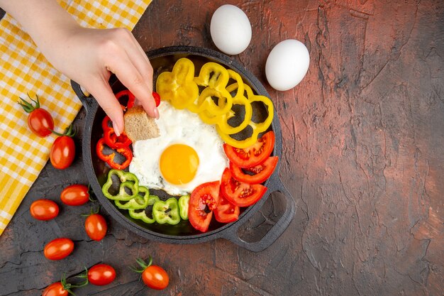 Bovenaanzicht smakelijke omelet met tomaten en gesneden paprika op de donkere tafel