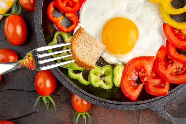 Bovenaanzicht smakelijke omelet met tomaten en gesneden paprika op de donkere tafel