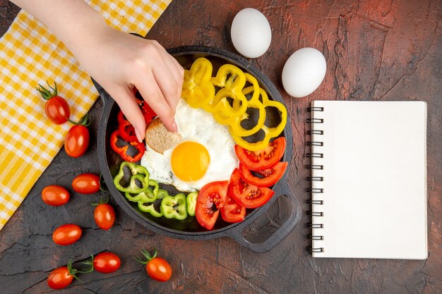 Bovenaanzicht smakelijke omelet met tomaten en gesneden paprika op de donkere tafel