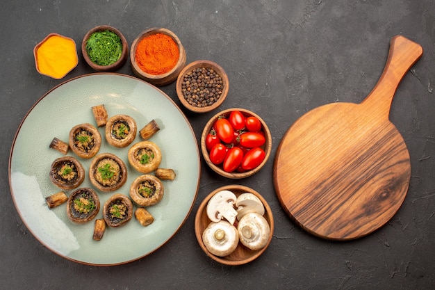 Bovenaanzicht smakelijke paddenstoelenmaaltijd met verse tomaten en kruiden op donkere vloerschotel dinermaaltijd kokende paddestoel