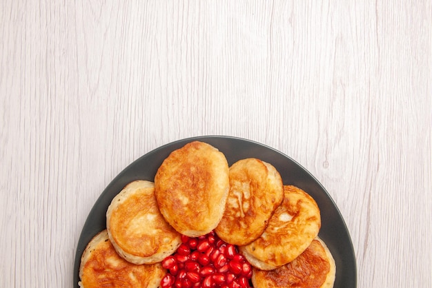 Bovenaanzicht smakelijke pannenkoeken plaat van een smakelijke pannenkoeken met zaden van granaatappel op de witte tafel