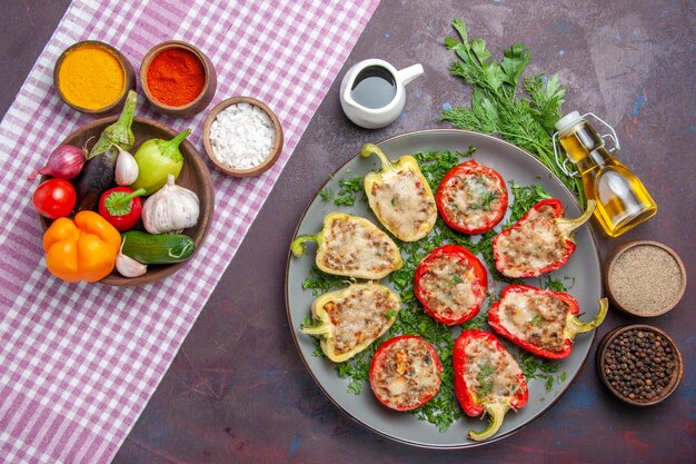 Bovenaanzicht smakelijke paprika's heerlijke gekookte maaltijd met vlees en groenten op donkere ondergrond dinerschotel peper gekruid eten