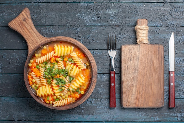 Gratis foto bovenaanzicht smakelijke pastasoep van spiraalvormige italiaanse pasta met groen op het donkerblauwe bureau soepschotel kleur italiaanse pastakeuken