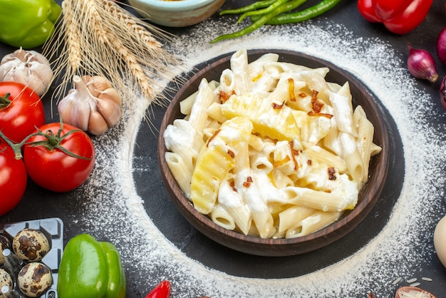 Bovenaanzicht smakelijke penne pasta in kom rode uien knoflook kwarteleitjes tomaten op tafel