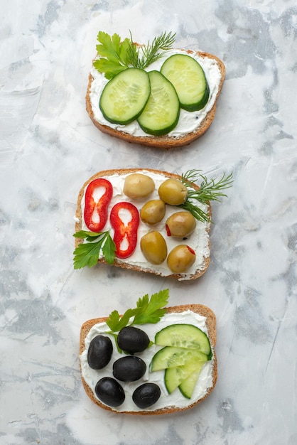Bovenaanzicht smakelijke sandwiches met komkommers en olijven witte achtergrond lunch eten sandwich horizontale maaltijd hamburger brood toast