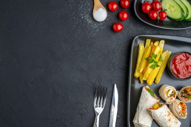 Bovenaanzicht smakelijke shaurma gesneden pitabroodje met frietjes en ketchup op donkere ondergrond