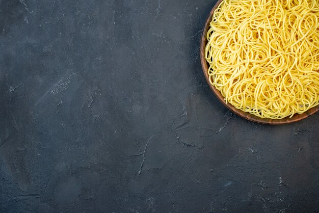 Bovenaanzicht smakelijke spaghetti in kom op zwarte tafel met kopieerplaats