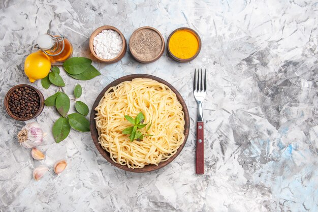 Bovenaanzicht smakelijke spaghetti met kruiden op witte deegschotel pastamaaltijd