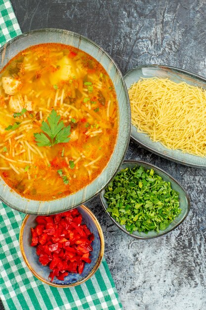 Bovenaanzicht smakelijke vermicellisoep met greens en rauwe vermicelli op lichtgrijze tafel