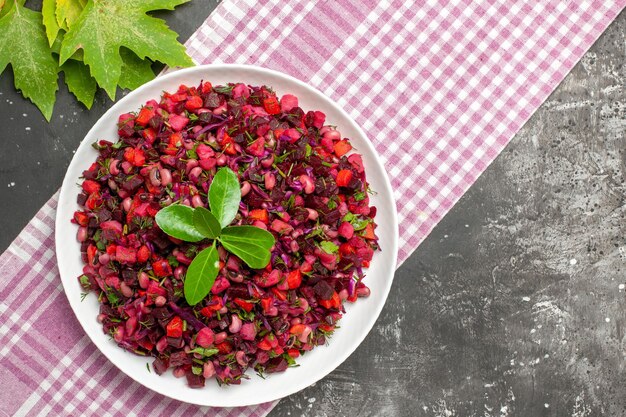 Bovenaanzicht smakelijke vinaigrette bietensalade binnen plaat op het donkere oppervlak