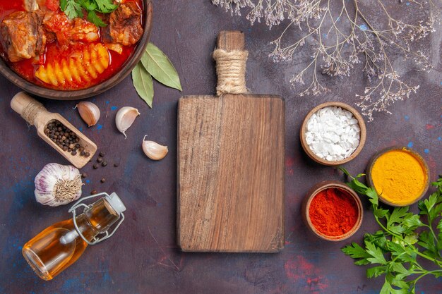 Bovenaanzicht smakelijke vleessoep met knoflook en kruiden op zwart