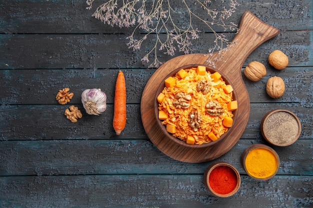 Bovenaanzicht smakelijke wortelsalade met walnoten en kruiden op donkerblauwe notensalade gezondheidsdieet kleur voedsel