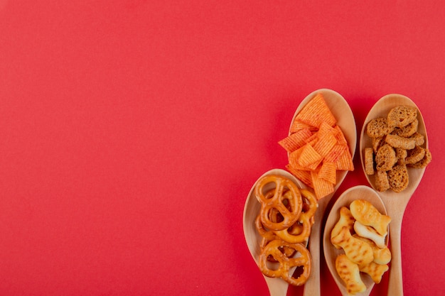 Gratis foto bovenaanzicht snacks paprika chips harde chuck mini brezel en vis crackers aan de linkerkant met kopie ruimte op rode achtergrond