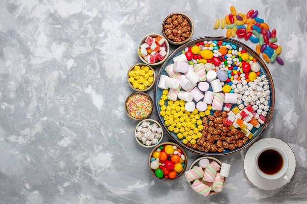 Bovenaanzicht snoep samenstelling verschillende gekleurde snoepjes met marshmallow en thee op witte bureau suiker snoep bonbon zoete confitures