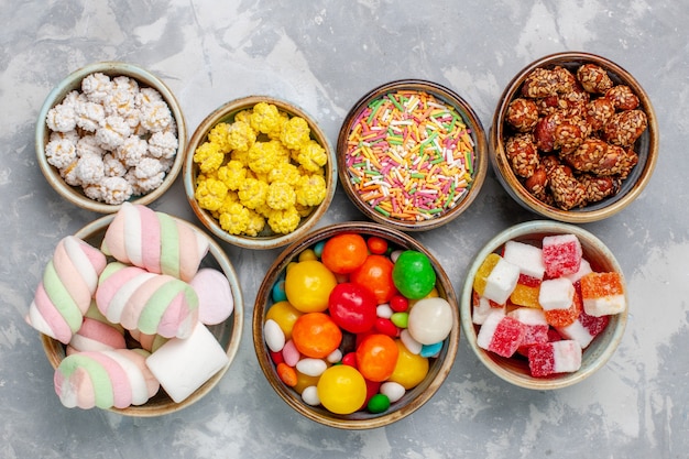 Bovenaanzicht snoep samenstelling verschillende gekleurde snoepjes met marshmallow in potten op witte bureausuikergoed bonbon zoete confiture