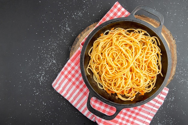 Bovenaanzicht spaghetti koekenpan op houten bord op donkere achtergrond