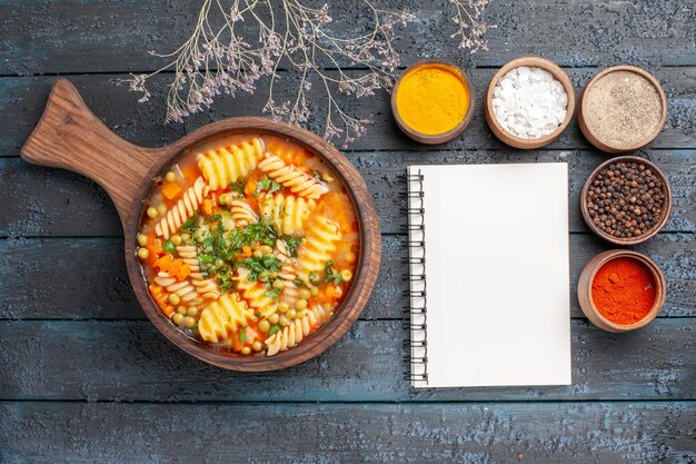 Bovenaanzicht spiraal pasta soep heerlijke maaltijd met verschillende smaakmakers op het donkere bureau soep kleur italiaanse pasta gerecht keuken