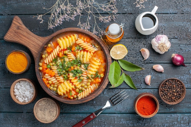Bovenaanzicht spiraalvormige pastasoep met kruiden op donkerblauwe bureausoepsauskleur Italiaanse pastakeukenschotel