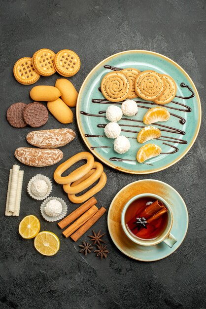 Bovenaanzicht suiker koekjes met snoepjes en kopje thee op grijze achtergrond