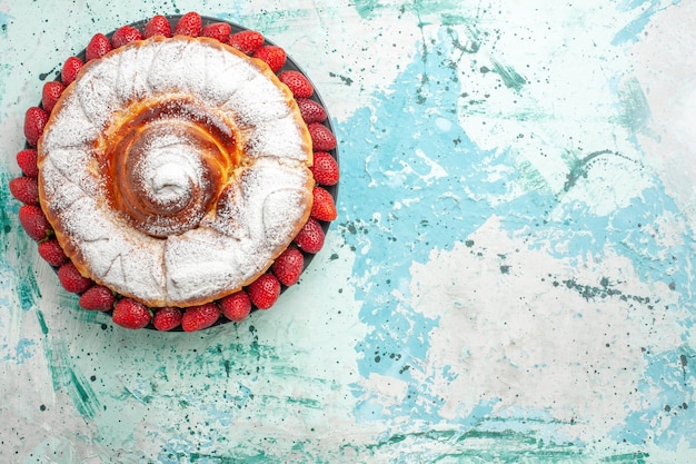 Bovenaanzicht suiker poeder cake met verse rode aardbeien op het lichtblauwe oppervlak