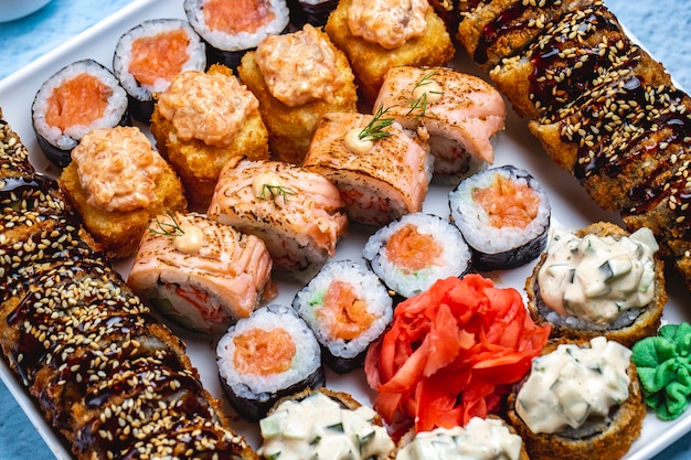 Bovenaanzicht sushi set hete sushi roll met teriyaki saus en sesamzaadjes Philadelphia met zalm sake maki wasabi en gember op een bord