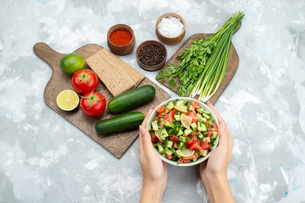 Bovenaanzicht tafel met groenten zoals tomaten, komkommers en samen met citroenen chips en groenten op wit, salade plantaardig voedsel