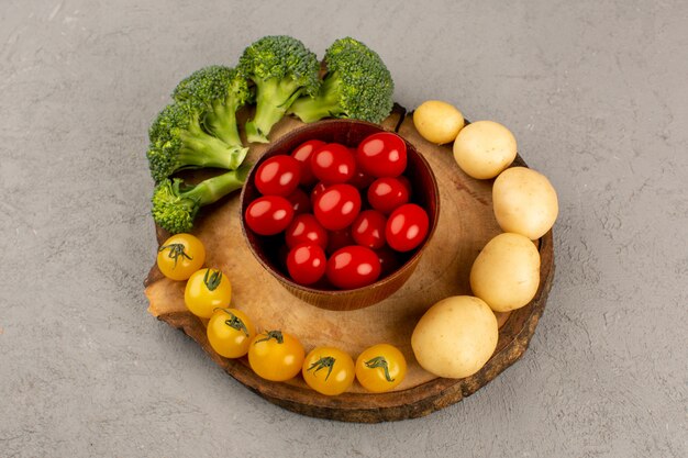 Bovenaanzicht tomaten rood geel langs groene broccoli en champignons op het grijze bureau