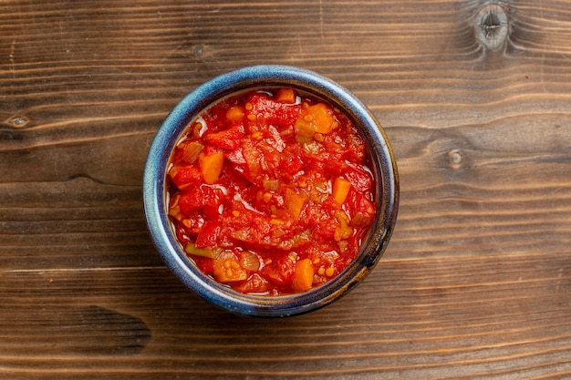 Bovenaanzicht tomatensaus met groenten op bruine achtergrond maaltijdsaus tomatengroente