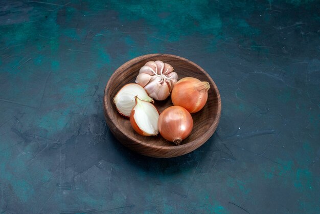 Bovenaanzicht uien met knoflook in plaat op donker