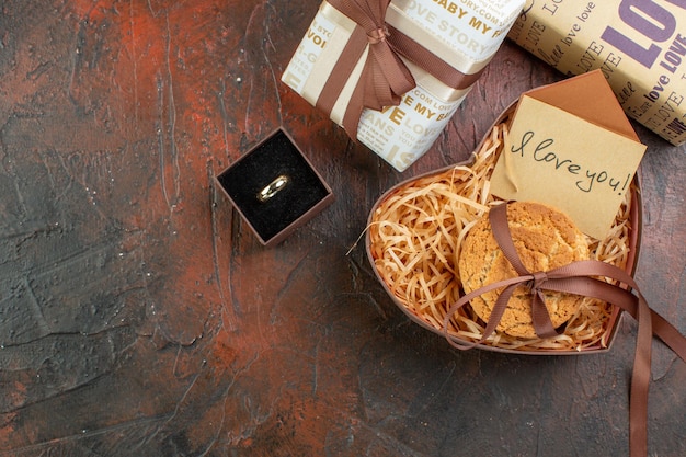 Bovenaanzicht Valentijnsdag cadeautjes met ring en koekjes op de donkerbruine achtergrond liefde paar kleur cadeau gevoel huwelijk vakantie