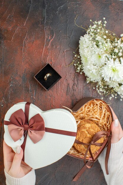 Bovenaanzicht Valentijnsdag present klein koekje met bloemen op een donkere achtergrond liefdeskleur gevoel huwelijk vakantie paar cadeau