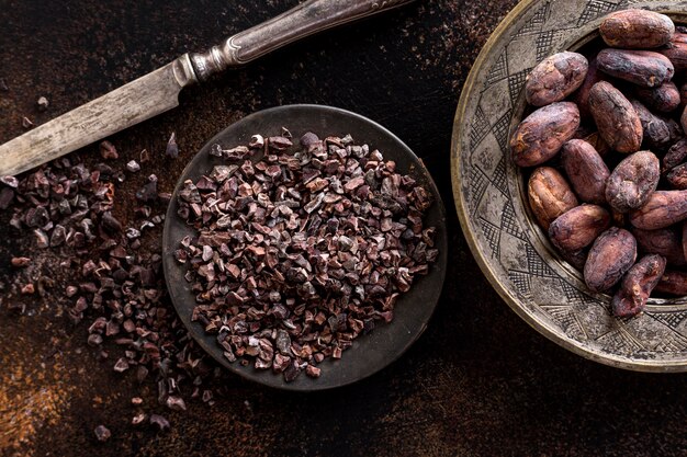 Bovenaanzicht van aan de grond gezette cacaobonen op plaat met mes en cacaobonen