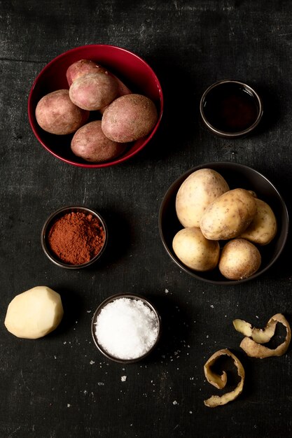 Bovenaanzicht van aardappelen in kommen met zout en specerijen