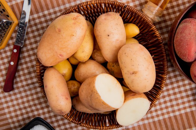 Bovenaanzicht van aardappelen in mand met mes op geruite doek achtergrond