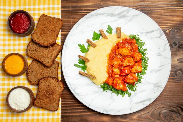 Bovenaanzicht van aardappelpuree met gesauteerde plakjes kip en brood op bruine tafel aardappelschotel maaltijd diner vlees