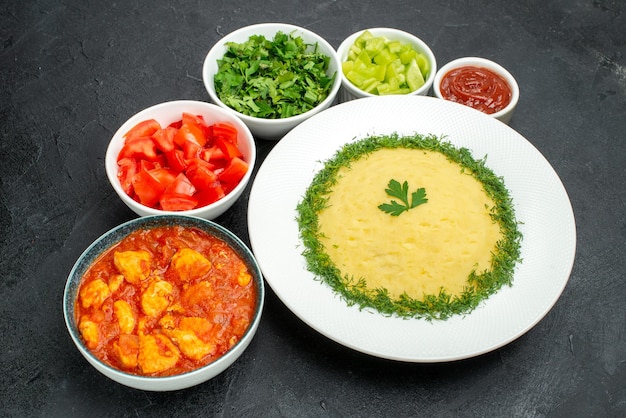 Bovenaanzicht van aardappelpuree met groenten en gesneden tomaten op grijze tafel